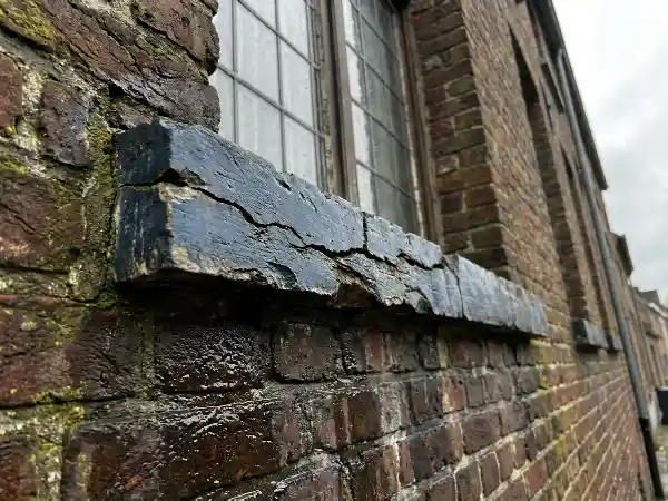 Gebarsten raamdorpel op een bakstenen gevel na een regenbui